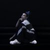 Rose Villain seduta su divano nero indossa il completo Firebird e le adidas Superstar nella campagna SS25