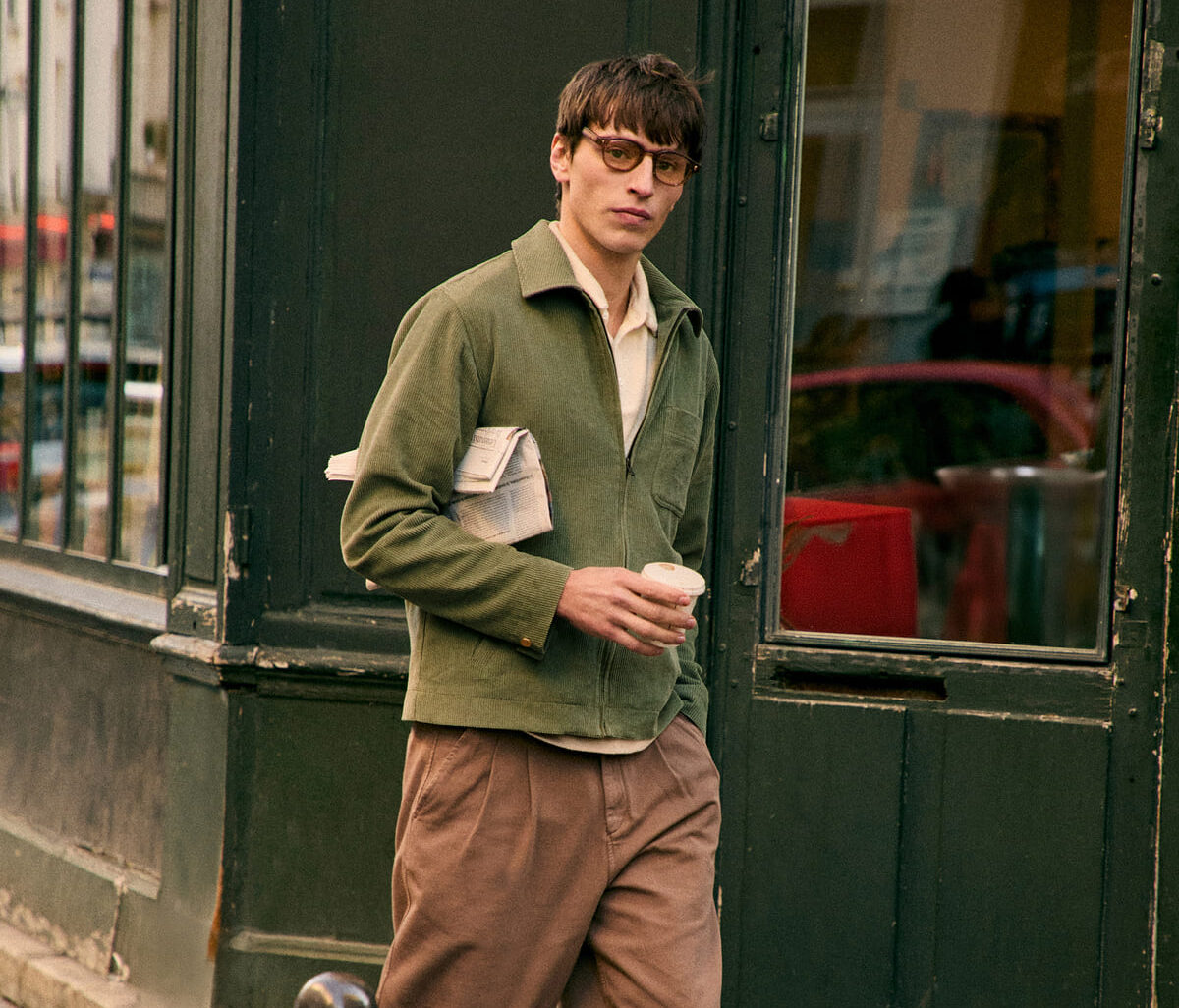 Look urbano con giacca verde e pantaloni beige davanti a un bistrot parigino